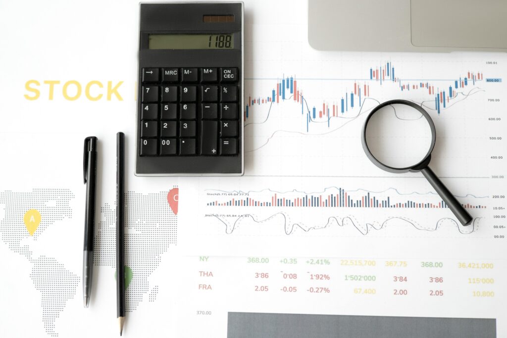 Flat lay of stock market analysis tools including calculator, graphs, and magnifying glass.